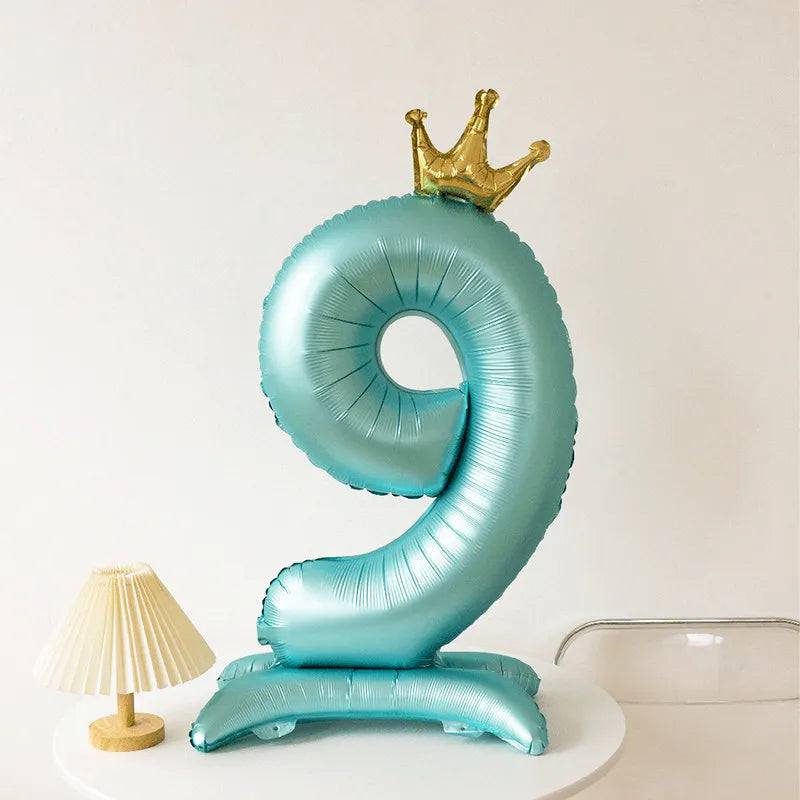 A light blue foil balloon shaped like the number 9 with a gold crown on top.