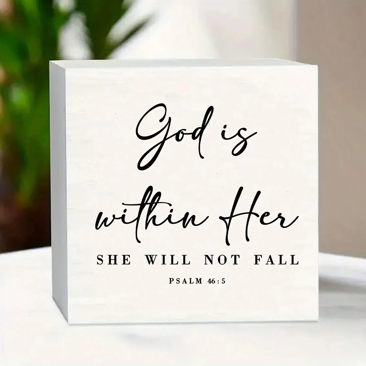 A white wooden desktop ornament featuring the Bible verse God is within Her from Psalm 46:5