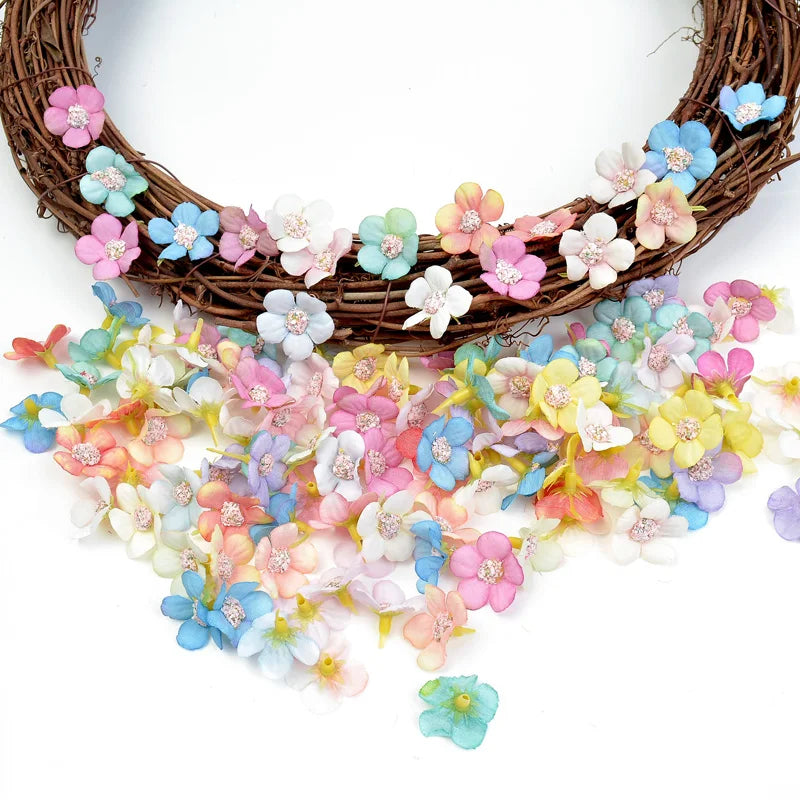 A wreath of small silk artificial flowers in pastel pink, blue, and yellow scattered below.