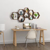 A set of four wooden hexagon floating shelves mounted on a white wall above a light wood desk.