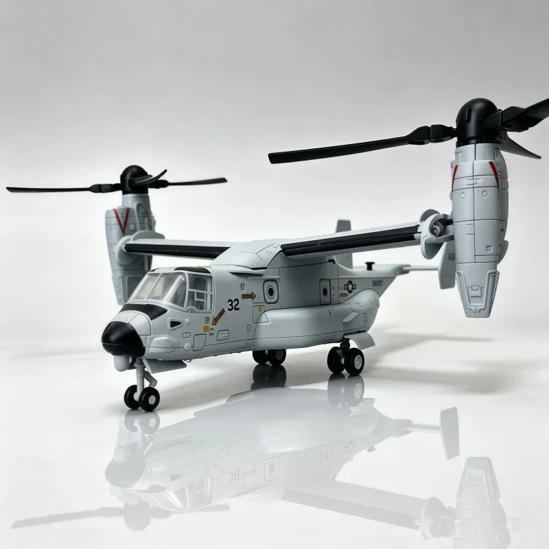 A gray V-22 Osprey tiltrotor model kit with rotors and landing gear is displayed on a reflective surface.