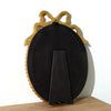 A vintage bowknot picture frame in black with gold accents, displayed on a wooden surface.
