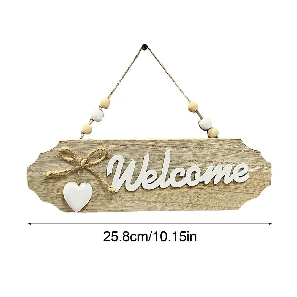 A wooden welcome sign with the word Welcome carved into it and adorned with small white beads on a string.