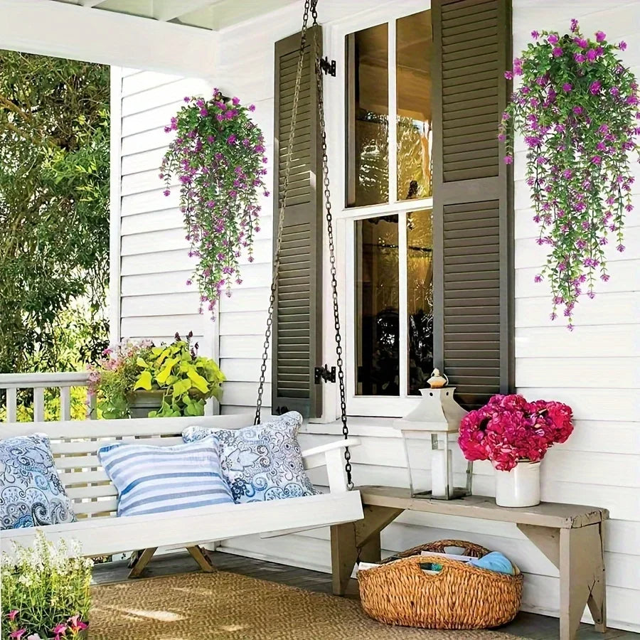 Three faux eucalyptus hanging plants displayed on a white porch with greenery and flowers.