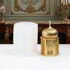 A golden silicone candle mold set featuring a fluted candle holder and a white pillar candle on a white surface.