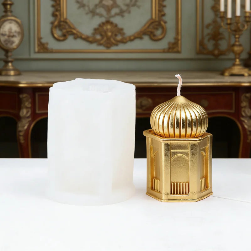 A golden silicone candle mold set featuring a fluted candle holder and a white pillar candle on a white surface.