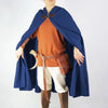 A person wearing an orange shirt and white pants with a deep blue velvet hooded cloak and brown leather belt.
