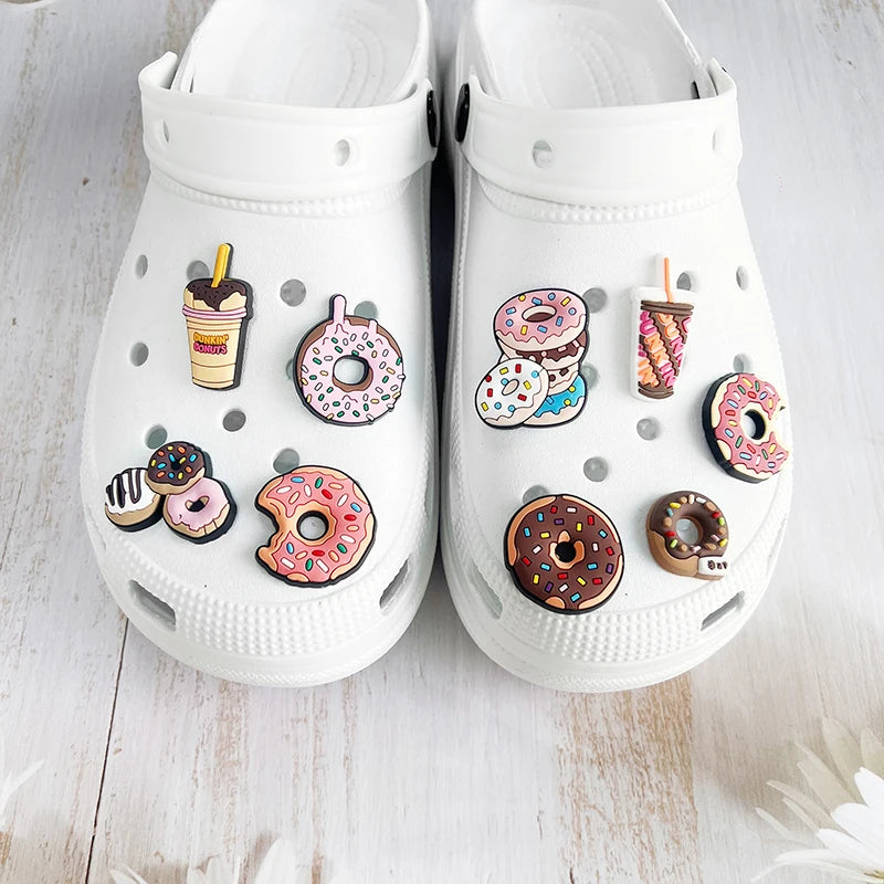 A pair of white Crocs featuring various doughnut-themed charms and decorations.