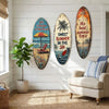 Decorative wooden surfboard wall art featuring tropical scenes and text on a white wall.