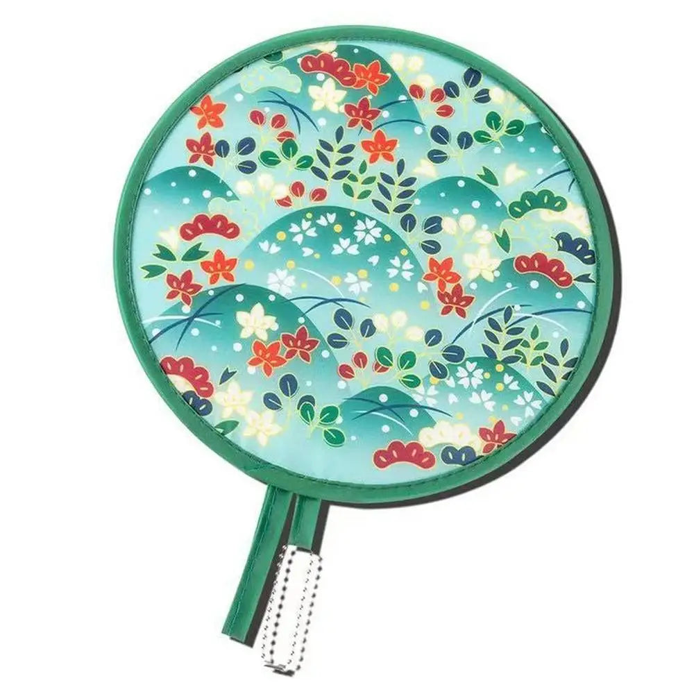 A teal fabric fan with a floral pattern, featuring red and green leaves and small white flowers.