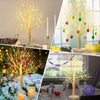 A decorative LED birch tree with warm yellow lights and hanging ornaments displayed in various settings.