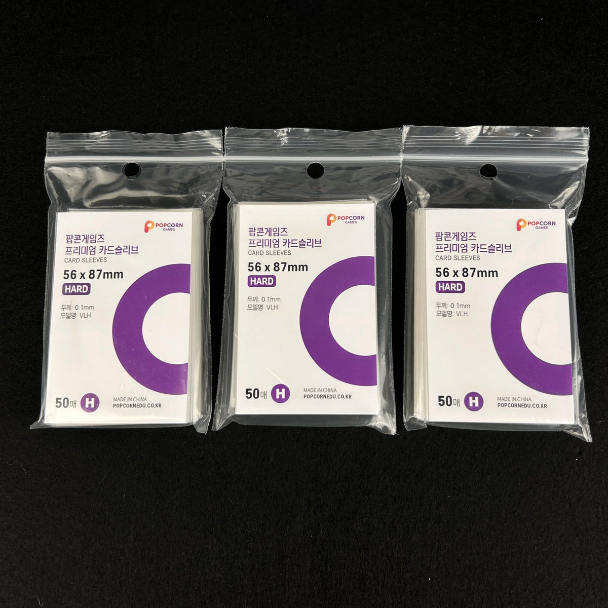 Three packages of clear protective card sleeves labeled 56 x 87mm with purple and white text