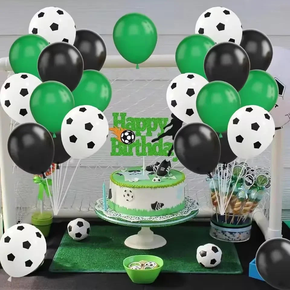 A display of black and green latex balloons, a cake, and soccer balls for a football themed party.