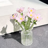 A bouquet of pink and yellow hand-blown glass flowers in a clear glass vase