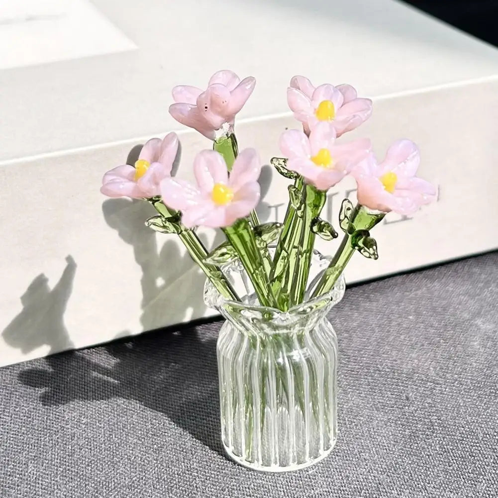 A bouquet of pink and yellow hand-blown glass flowers in a clear glass vase