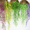A collection of artificial plant vines in various shades of green, yellow, and purple hanging from a woven basket