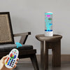 A color-changing LED fish lamp is displayed on a wooden table next to a person holding a remote control.