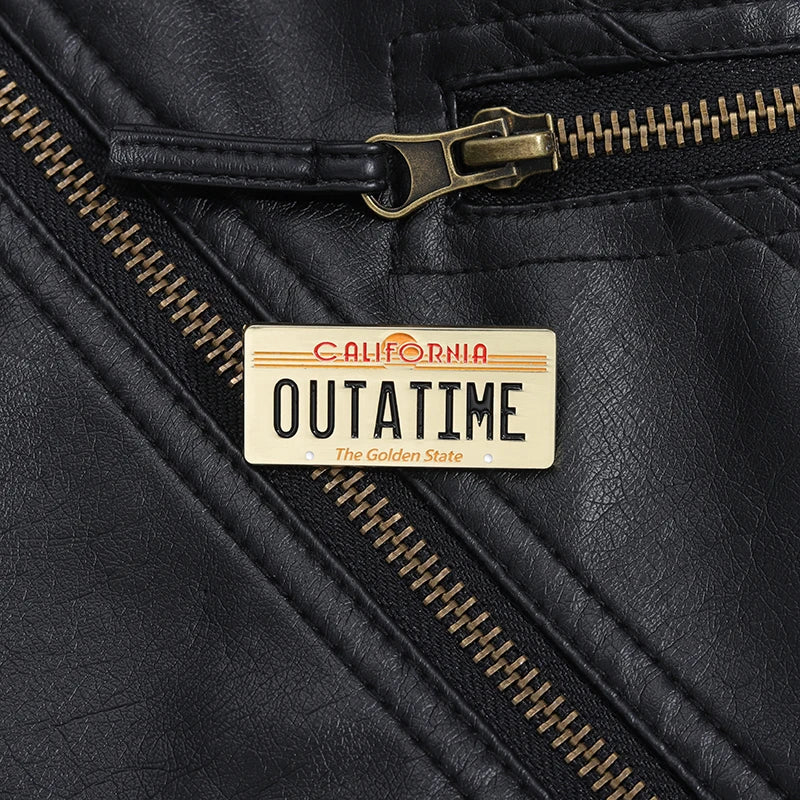 A black leather jacket detail showing a gold zipper and an Outatime license plate enamel pin.