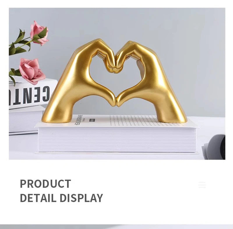 Gold heart-shaped resin hand sculpture displayed on a white book for detail view.