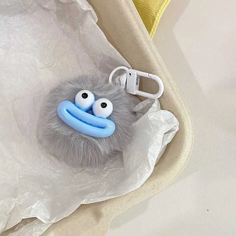 A fluffy gray sausage mouth plush charm with blue eyes and a white plastic keychain attached.