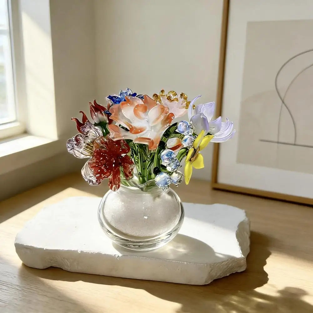 A bouquet of handcrafted blue glass flowers in a clear vase displayed on a white stone slab.