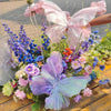 A vibrant floral arrangement featuring pink, purple, and blue silk artificial butterflies.