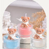 Three bear aromatherapy candles in glass jars with ribbons displayed on a white surface.