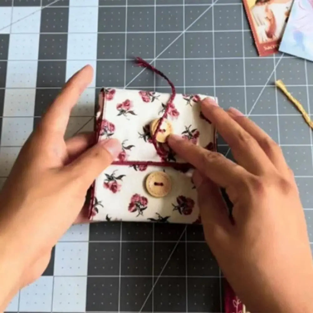A pair of hands is opening a handcrafted pocket devotional with a cross-shaped pouch decorated with floral patterns.