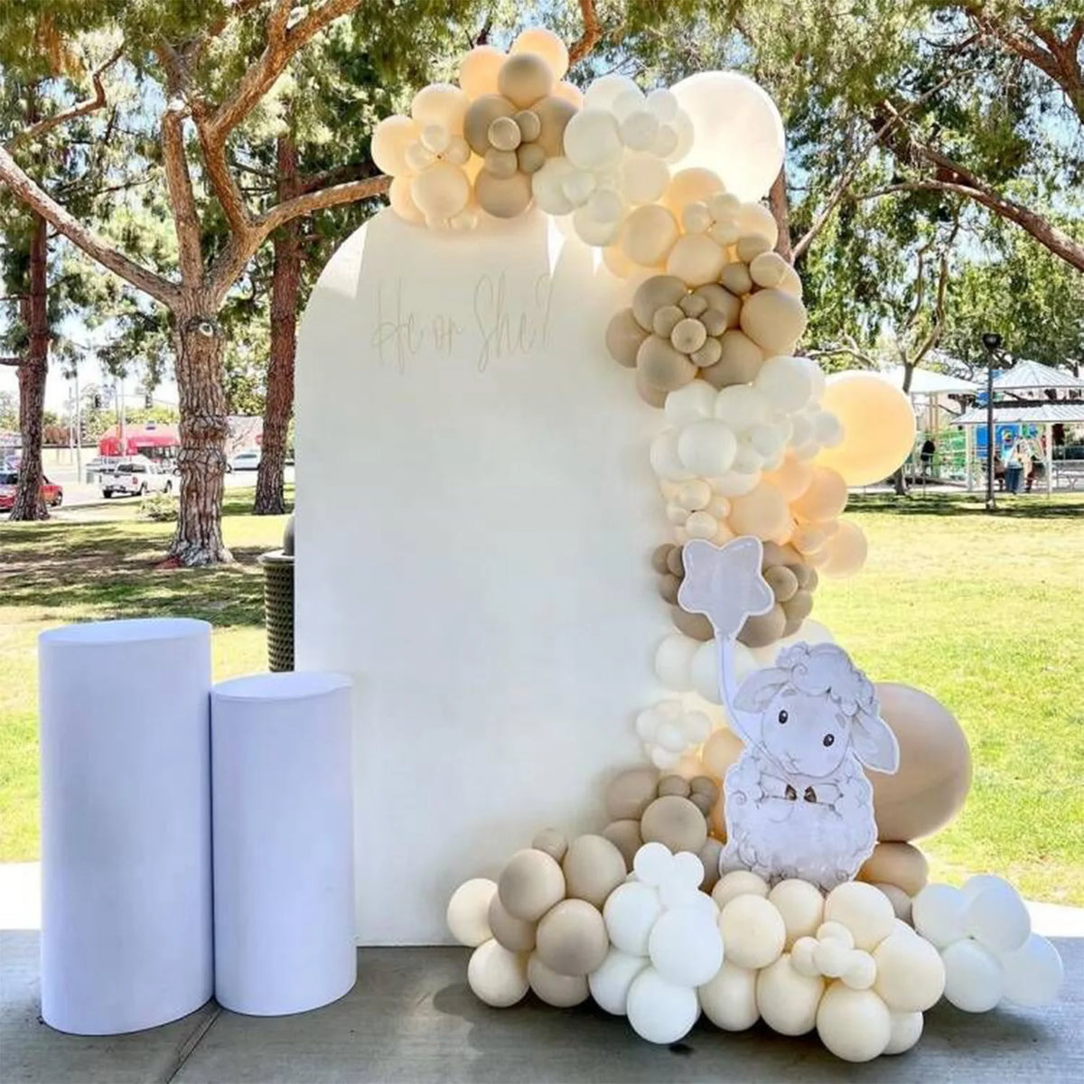 A white arch backdrop decorated with cream and beige balloons and a white rabbit figure for an event