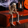Three resin skeleton skull figurines are displayed on a wooden box with an antique lantern.