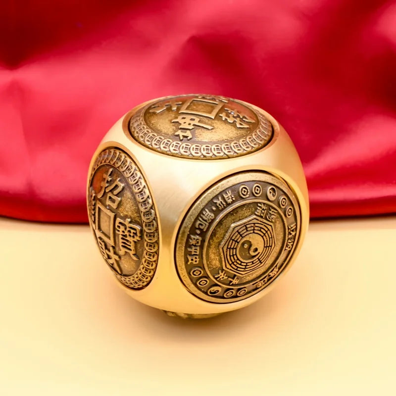 A brass Chinese lucky coin spinner fidget toy with intricate engravings resting on a light background.