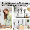 A woman is decorating a wall with three black metal flower arrangements, showcasing rustic metal flower wall art.