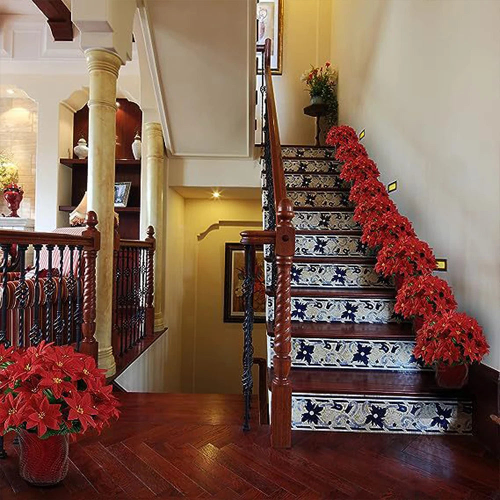 A staircase decorated with bright red artificial poinsettia flowers on the banister and steps.