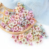 A collection of pink and white silk artificial flower heads arranged on a bamboo tray.