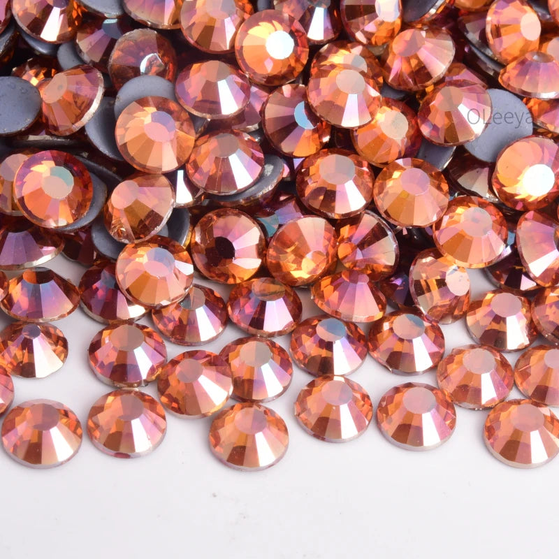 A close-up view of mixed sized crystal and crystal AB glass rhinestones in shades of warm orange and amber.