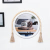 A round mirror framed by a beaded wreath hangs on a white wall.