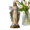 A religious figurine of the Blessed Mother with a halo, draped in blue and white robes, standing next to a vase of pink tulip