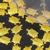 Goldene Geld-Schildkrötenfiguren verstreut auf dunker Oberfläche mit feinem Goldnetz.
