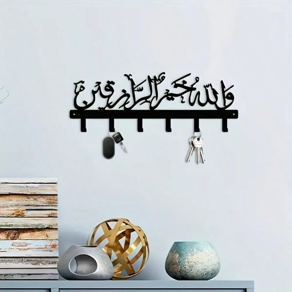 Black Islamic Arabic blessing key holder with hooks mounted on a white wall.