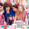 A group of children celebrating with red bow number candles on a birthday cake.