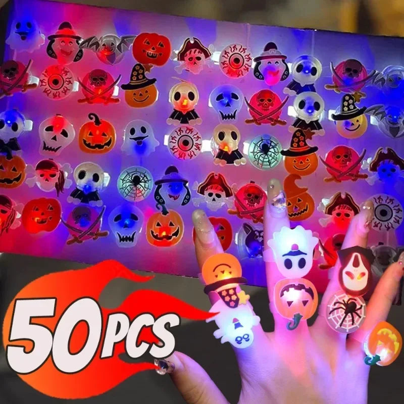 A hand holds a collection of glow-in-the-dark Halloween rings with flashing lights against a dark background.