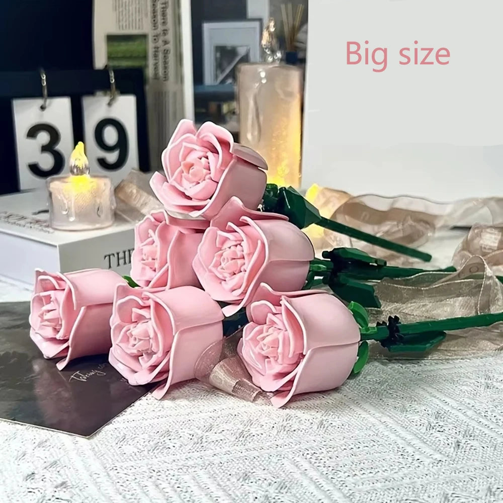A bouquet of pink rose flower building blocks displayed next to a lit candle.