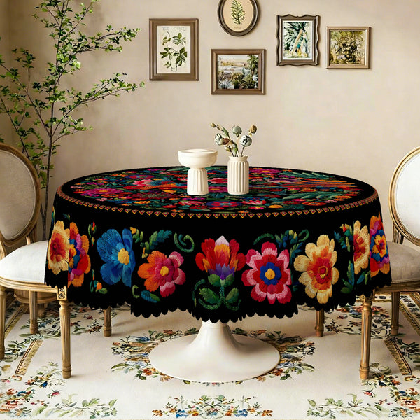 A black embroidered tablecloth with vibrant floral patterns is displayed on a round table in a softly lit room.