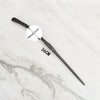 A black metal magic wand replica with a circular label marked Metal Core is displayed on a white marble surface.