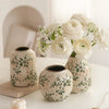 A grouping of handmade ice crackle ceramic vases holding white roses and greenery.