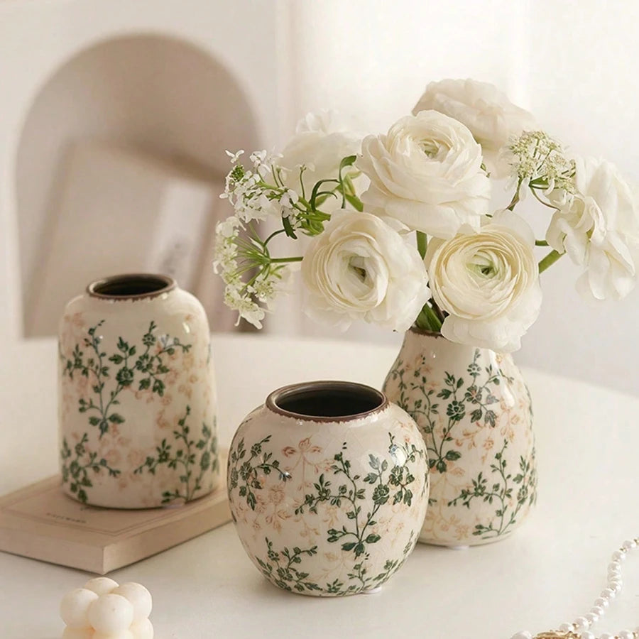 A grouping of handmade ice crackle ceramic vases holding white roses and greenery.