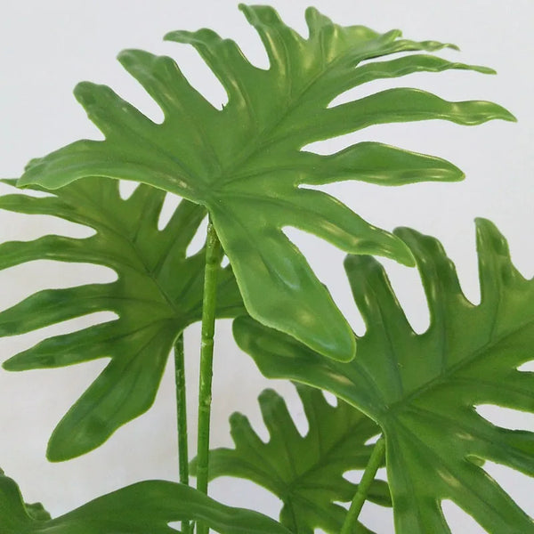 Green artificial monstera palm tree leaves on a stem for home decor
