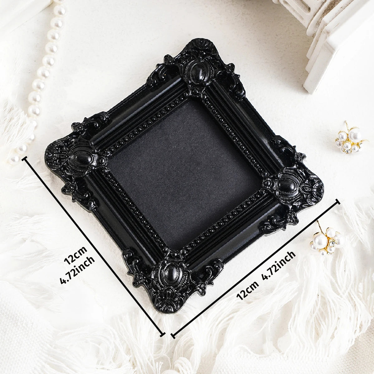 Black ornate picture frame with gold accents displayed on a white textured surface.