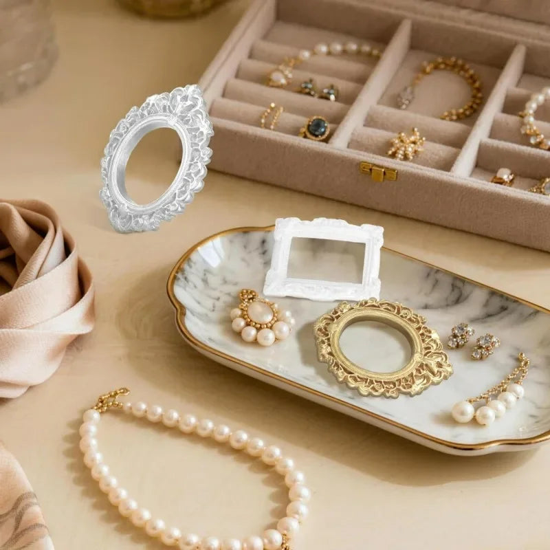 A collection of vintage resin picture frames, including a white oval frame and gold circular frames, displayed on a marble tr