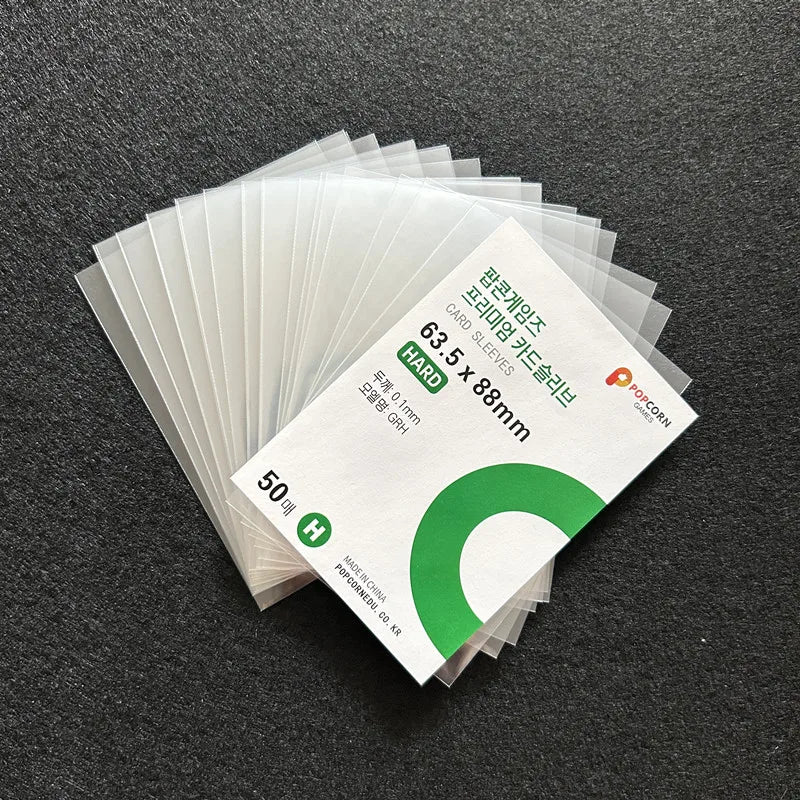 A stack of 50 clear plastic card sleeves with green and white text is shown on a dark gray surface.